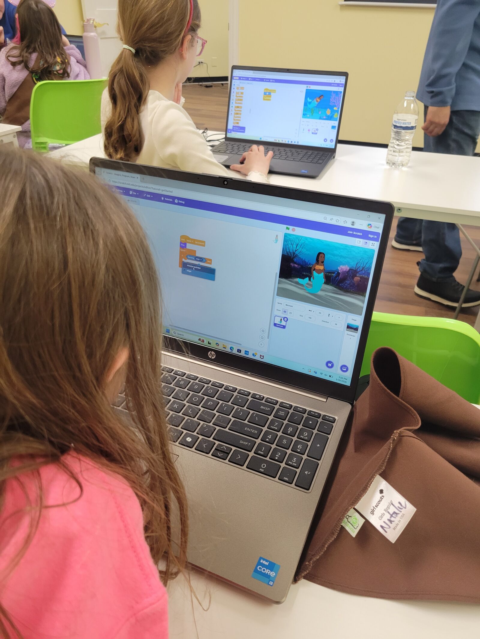 A student building a Scratch project on a laptop during a coding class