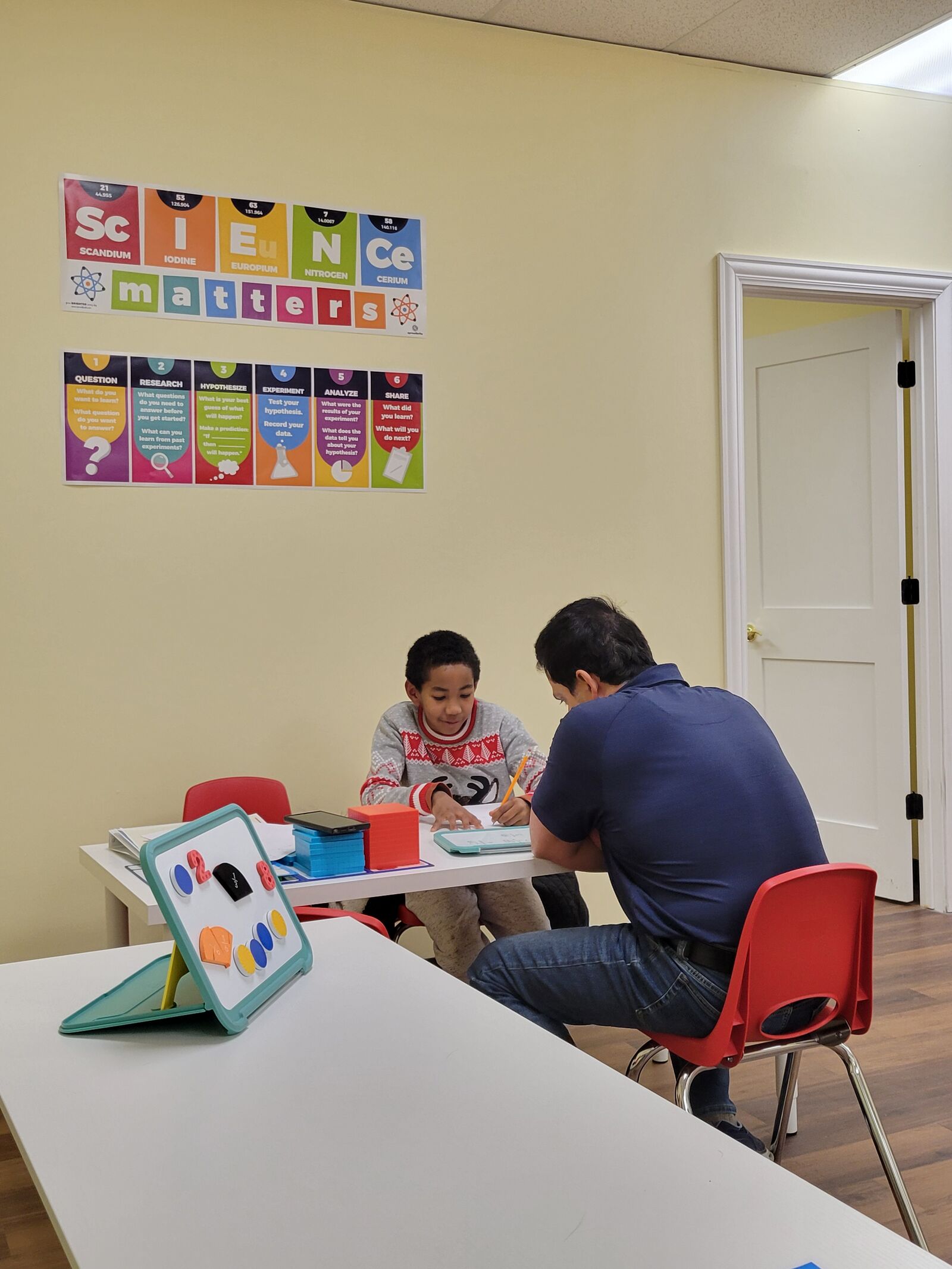 A tutor working through math with a student using hands-on manipulatives