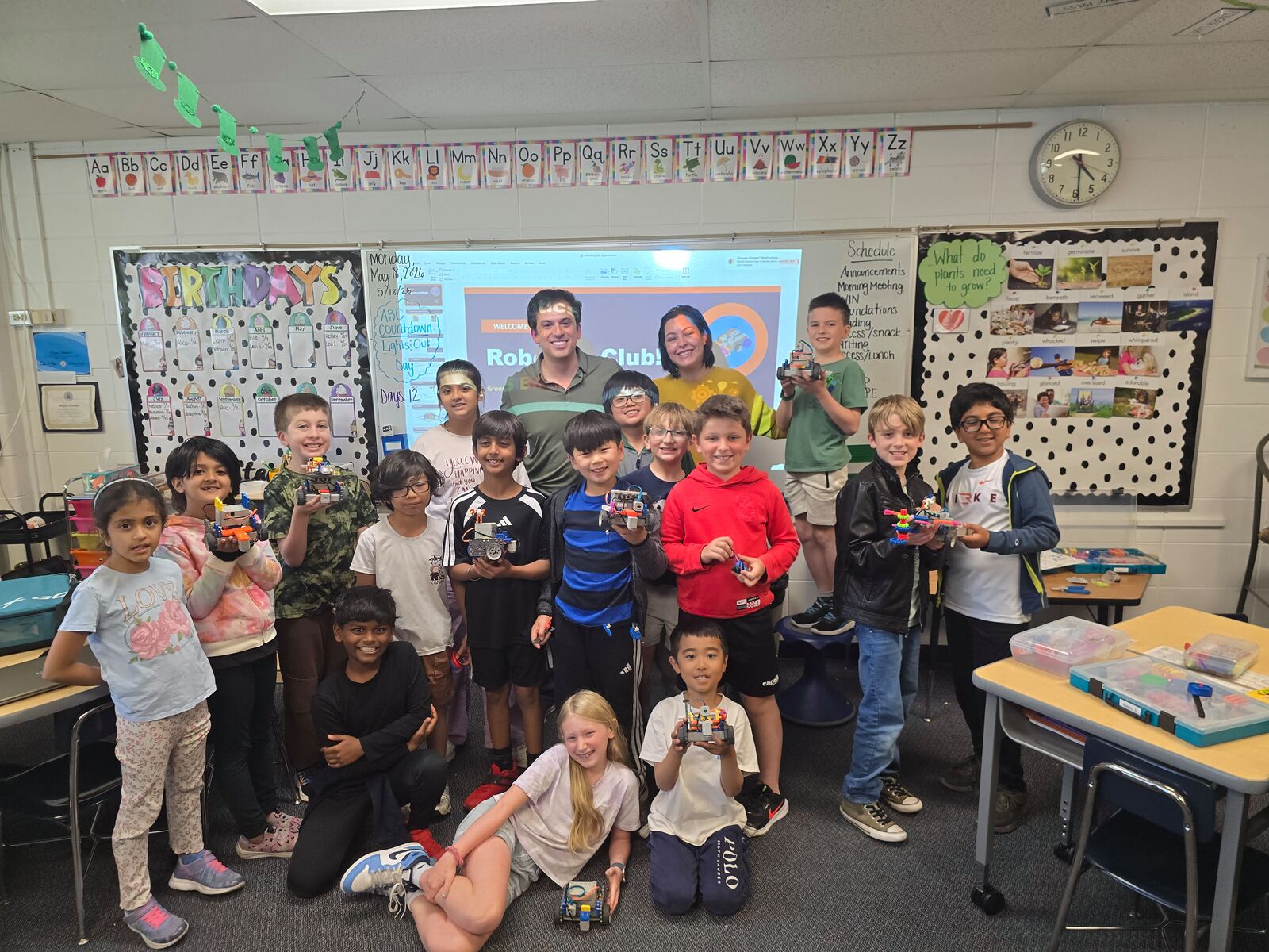 Robotics Club students holding their robots in a classroom group photo